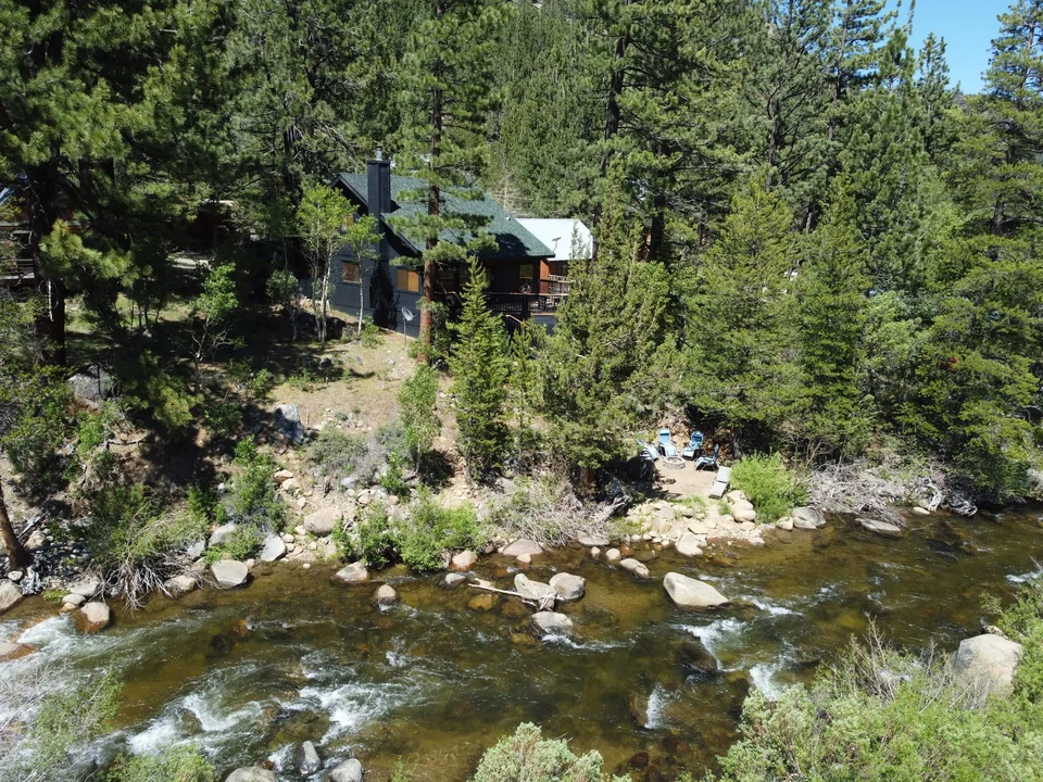 Tahoe River Cabin tucked among pine trees above the rocky Carson River shoreline.