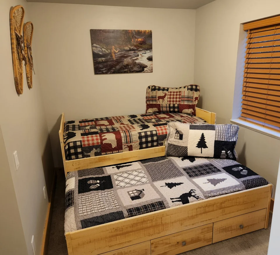 Two twin sleeping spaces in the upstairs kids’ loft, with the lower trundle bed pulled out beneath the upper bed.